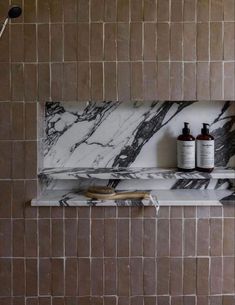 a bathroom with marble tile and two bottles on the shelf