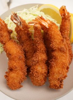 fried shrimp and coleslaw on a plate with lemon wedges