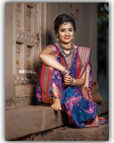 a woman sitting on the steps wearing a colorful sari and jewelry, posing for a photo