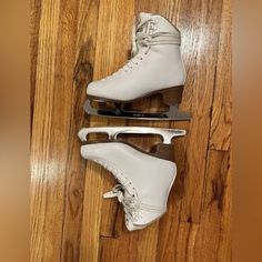 two pairs of ice skates sitting on top of a wooden floor