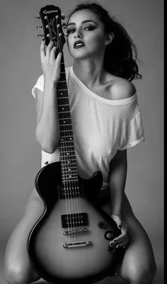 a woman is holding an electric guitar and posing for a photo in black and white