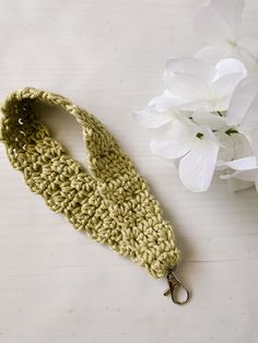 a crocheted key fob is laying next to a white flower on a table