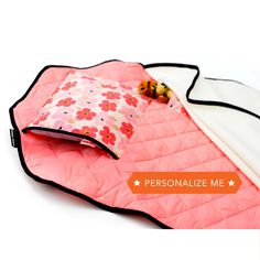 a pink and white blanket with a ladybug on it, sitting next to a pillow that says personalize me