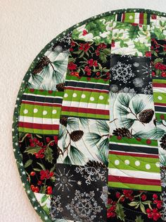 a green and red patchwork plate with pine cones, holly berries and snowflakes on it