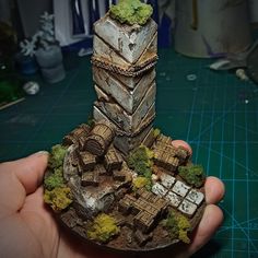 a person holding up a miniature tower with moss growing on it