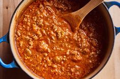 a pot filled with chili and meat on top of a wooden table