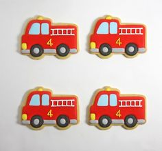 four decorated cookies with the shape of a firetruck and number 4 on them