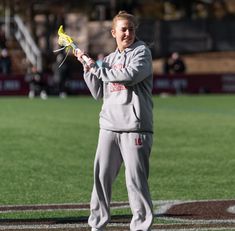 a man holding a lacrosse stick on top of a field