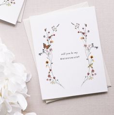 two greeting cards with flowers on them next to some white flowers and one has the words, will you be my flower girl?