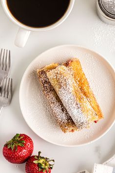 two pieces of cake on a plate next to strawberries and a cup of coffee