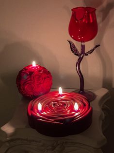 a candle that is sitting next to a vase with roses on it and a red rose in the middle