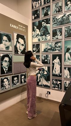 a woman standing in front of a wall with pictures on it