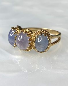 Star Sapphire Ring, Star Sapphire Ring for Women, Galaxy Ring, Celestial Ring, Vintage Star Sapphire Ring, Purple Star Sapphire, OOAK Ring A phenomenal vintage three stone ring featuring 3 purplish blue natural star sapphires with an approximate total weight of 6 carats, set beautifully and securely with multiple prongs in a split shank solid 14k yellow gold ring. The colors have been uniquely coordinated to create a blended Ombre effect, reminiscent of the early evening skies! * Ring size: US 5 Celestial Gemstone Rings For Formal Occasions, Celestial Style Cabochon Yellow Gold Rings, Celestial Yellow Gold Cabochon Rings, Celestial Oval Cabochon Rings, Star-shaped Gemstone Rings For Formal Occasions, Celestial Gemstone Rings, Celestial Style Open Ring With Gemstone, Celestial Style Gemstone Open Ring, Celestial Gemstone Open Ring