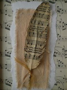 a piece of paper with music notes on it and a feather pinned to the side