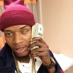 a man in a pink hat talking on a cell phone and holding money up to his ear