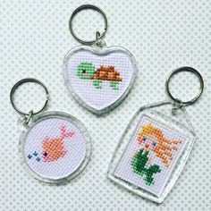 three cross stitch keychains with pictures of animals on them