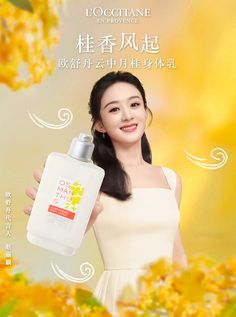 a woman holding up a bottle of body lotion in front of yellow and white flowers