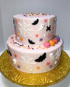 a three layer cake decorated with spooky bats and pumpkins on a gold platter