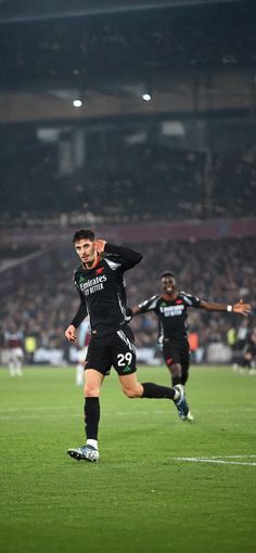 two soccer players are running on the field