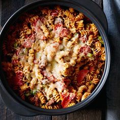 a bowl filled with pasta and meat on top of a wooden table