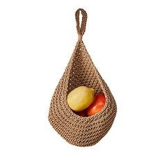 a brown basket with apples and an orange in it on a white background for use as a hanging ornament