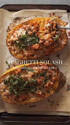 spaghetti squash stuffed with meat, cheese and spinach leaves on parchment paper in a baking pan