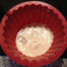 a red bowl filled with cream sitting on top of a counter