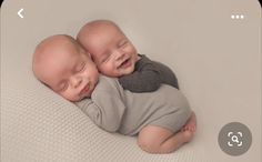 two baby babies cuddle together on a white blanket