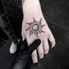 a person's hand with a sun tattoo on it