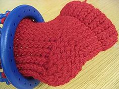 two red knitted mitts sitting on top of a blue object