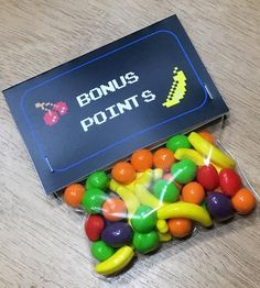 a box filled with lots of candy on top of a wooden table next to a sign