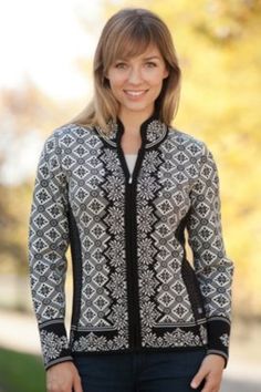 a woman standing in front of a tree wearing a black and white jacket with an intricate pattern