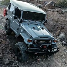 a grey jeep driving down a rocky road