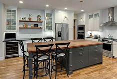 a kitchen with white cabinets and stainless steel appliances, wood flooring and counter tops