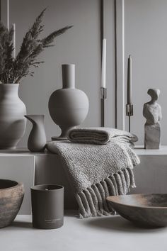 black and white photograph of various vases, candles, and towels on a table