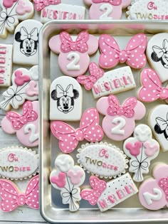 minnie mouse cookies decorated with pink and white icing are on a tray next to each other