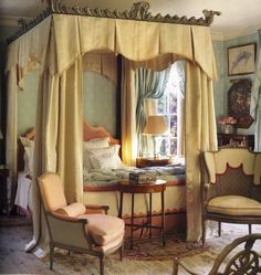 a canopy bed sitting in the middle of a bedroom next to two chairs and a table