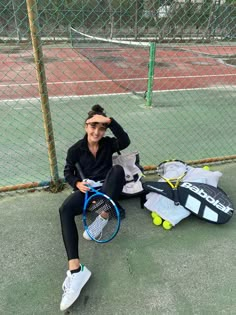 a woman sitting on the ground with tennis rackets