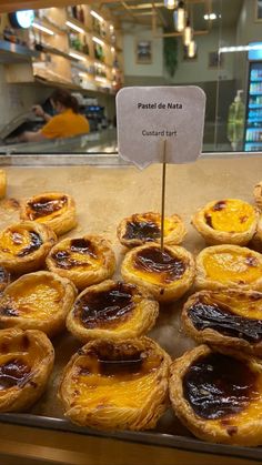 baked goods on display in a bakery with sign reading pastel de nats court tart