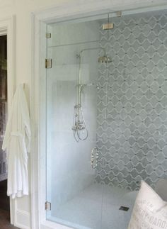 a bathroom with a walk in shower next to a white sink and bathrobe