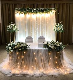 an image of a table set up with flowers and lights on the wall behind it