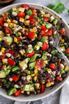 a large bowl filled with black beans, corn and avocado on top of a table