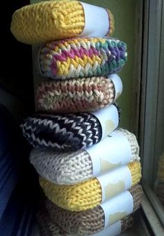 a stack of knitted towels sitting on top of a window sill