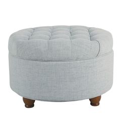 a round ottoman with wooden legs and buttons on the top, in light gray linen