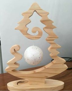 an ornament made out of wood with a white ball hanging from it