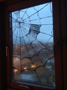 a broken glass window with some lights in the background