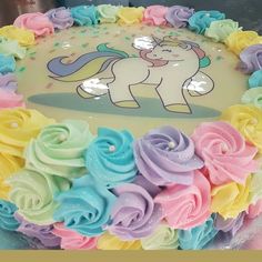 there is a cake decorated with icing and flowers on the top, as well as an image of a unicorn