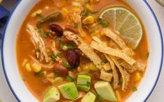 a white bowl filled with chicken tortilla soup and garnished with avocado