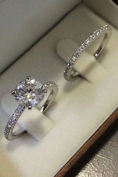 two engagement rings sitting in a box on top of a table