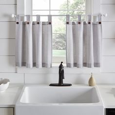 a white sink sitting under a window next to a counter top with a faucet